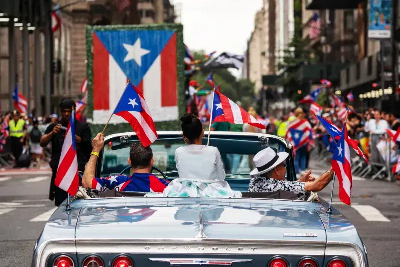 Puerto Rican day parade, people in a car waving flags at the parade, Fifth Avenue, Manhattan 