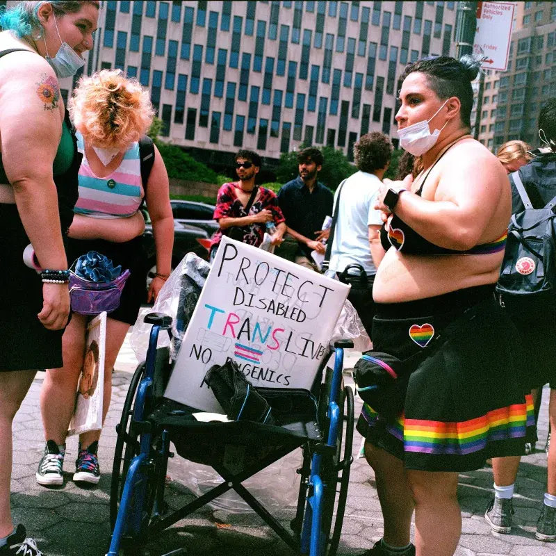 People around a wheelchair with a sign that says "protect disabled trans lived" at Washington Square Park