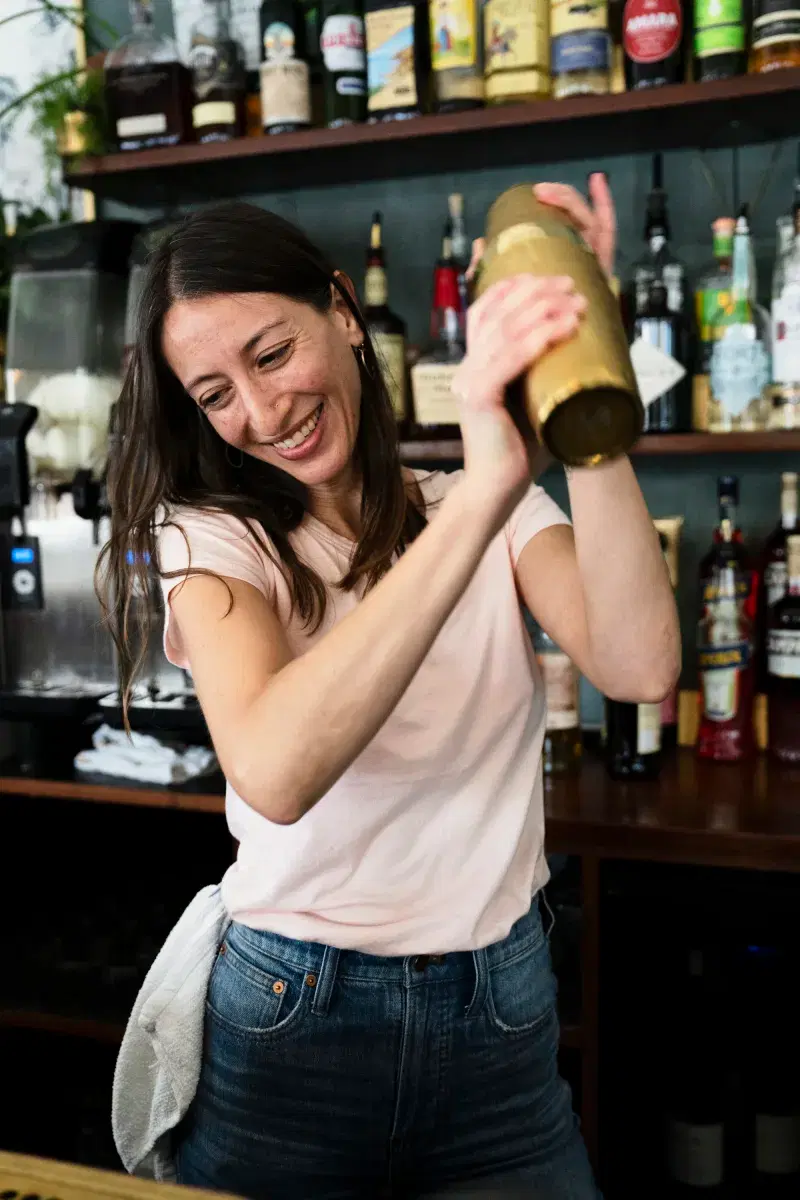 A person shakes a cocktail at the Esters bar